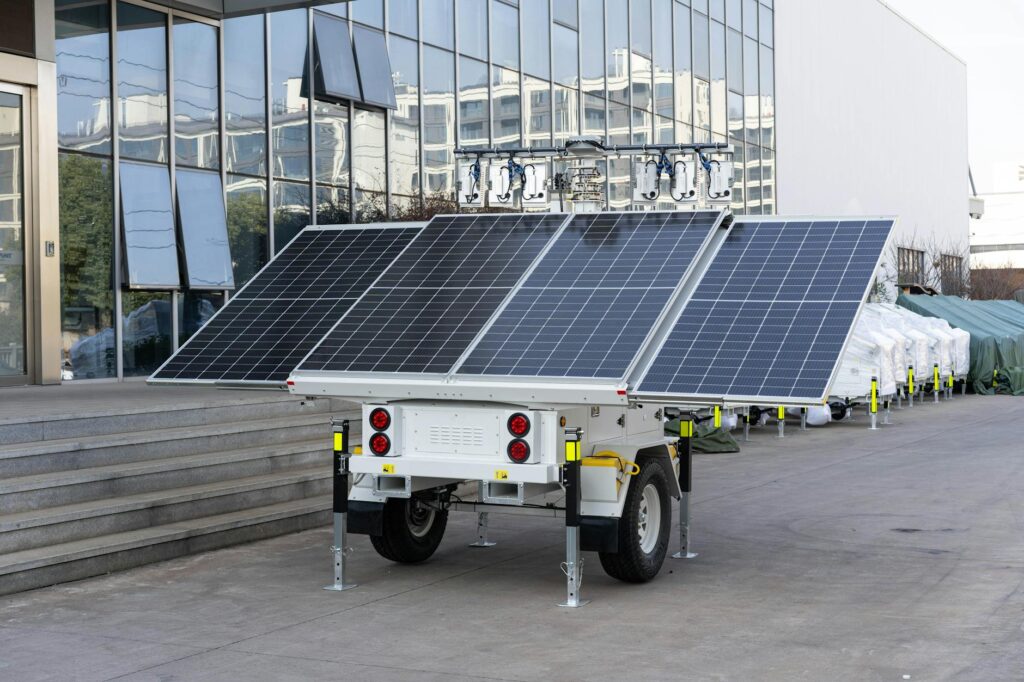 A mobile solar panel trailer parked outdoors by a modern building, showcasing renewable energy technology.