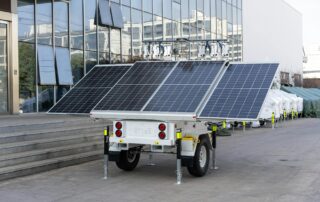 A mobile solar panel trailer parked outdoors by a modern building, showcasing renewable energy technology.